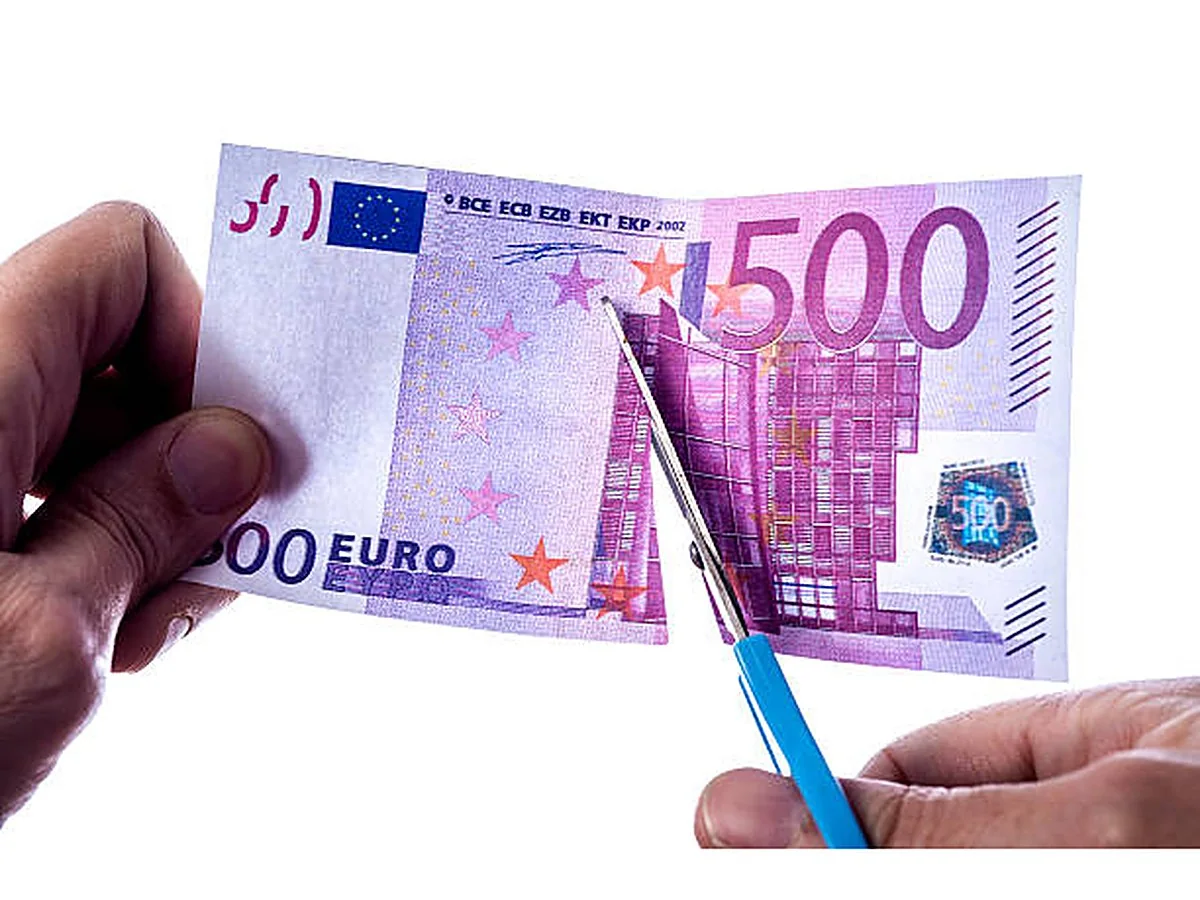 دستی با قیچی یک اسکناس 500 یورویی را میبرد تا صرفهجویی در هزینههای نگهداری را نشان دهد