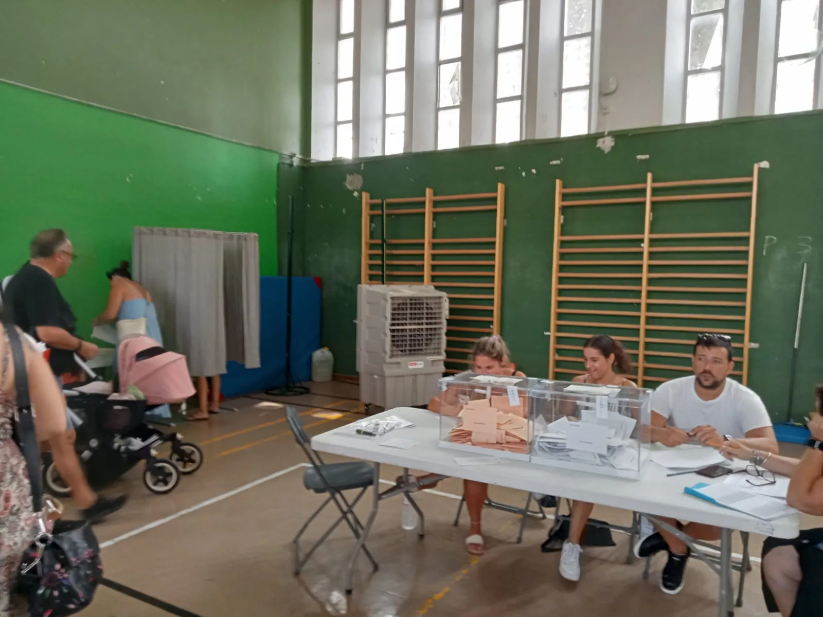 Mesa electoral en un polideportivo con climatizadores evaporativos PARS EcoTech al fondo