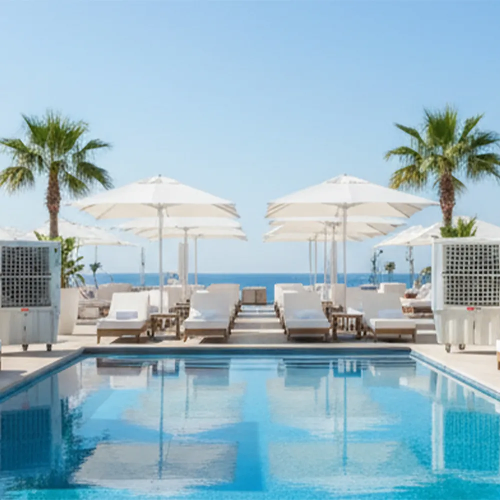 Climatizadores evaporativos ECO-15000 en una piscina junto al mar con tumbonas, sombrillas y palmeras